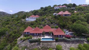 Uma propriedade numa encosta com vários edifícios de telhado vermelho, piscina e vegetação exuberante.