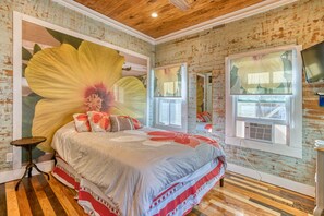 Quarto com uma cama grande, piso de madeira, um grande mural de flores e uma janela com vista.