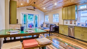 Une cuisine spacieuse avec un plancher en bois, un coin repas doté d’une table en verre et une vue sur l’extérieur.