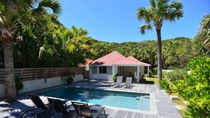 Ein Poolbereich mit Liegestühlen, einer überdachten Lounge und einem Holzdeck.