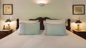 Una cama bien hecha con dos almohadas, un cabecero de madera y dos mesitas de noche con lámparas.