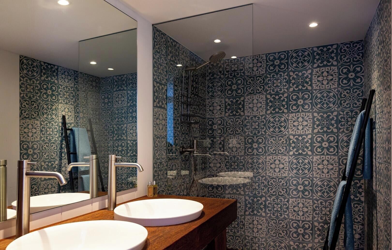 A bathroom with two sinks, a shower, and a mirror.