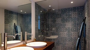 Un baño con dos lavamanos, una ducha y un espejo.