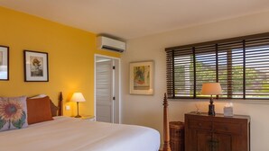Ein Schlafzimmer mit Bett, Nachttisch, Kommode und einem Fenster mit Jalousien.
