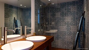 Een badkamer met twee wasbakken, een douche en een spiegel.