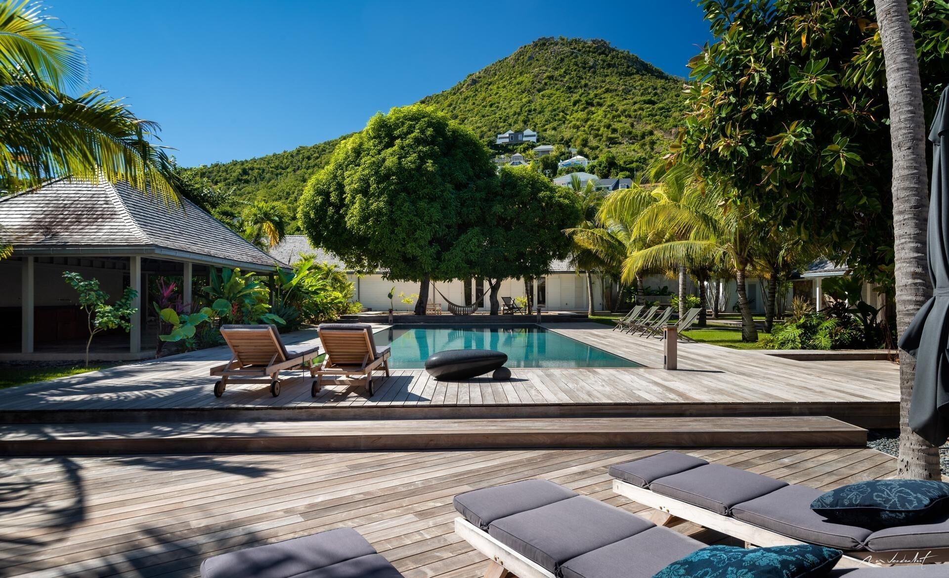 A pool area with lounge chairs and a wooden deck.