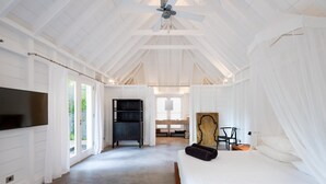 Ein Schlafzimmer mit Bett, Fernseher, Deckenventilator und Blick ins Freie.