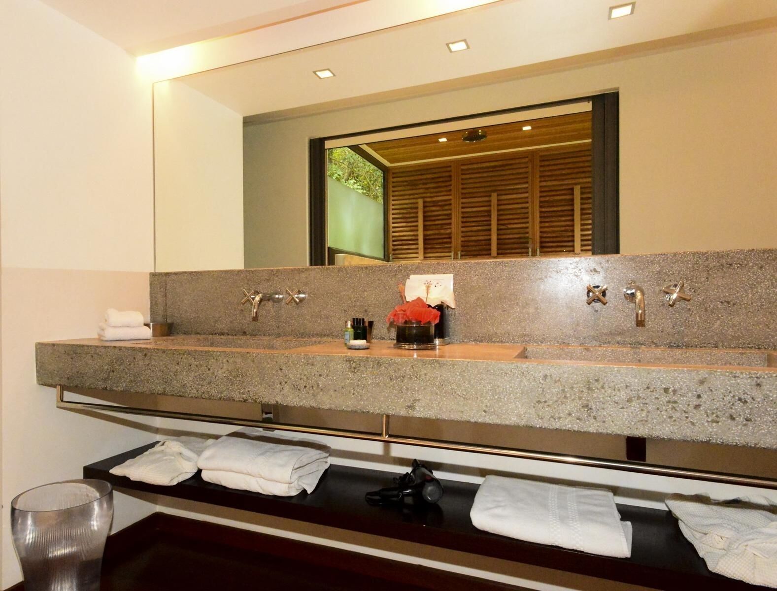 Une salle de bain moderne avec un comptoir en granit, un grand miroir et un mur recouvert de panneaux en bois.