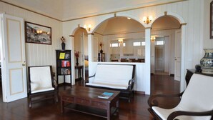 Amplia sala de estar con sofá, sillones, una mesa de centro y una estantería.