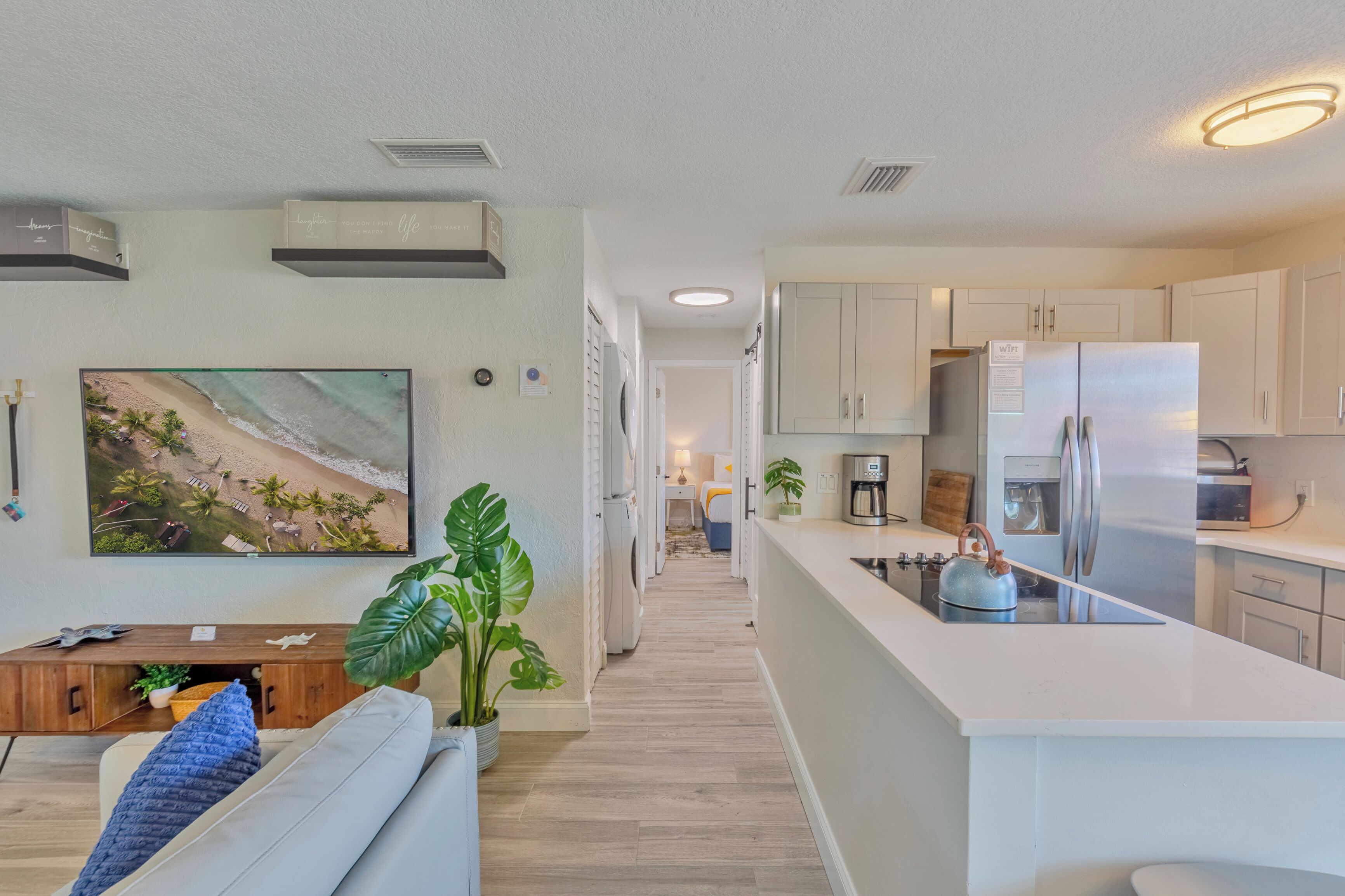 A modern kitchen with a central island, built-in appliances, and a view into the living area.