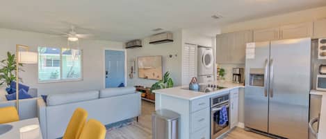 A modern kitchen with a central island, built-in appliances, and a dining area with yellow chairs.