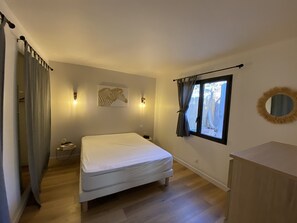 A bedroom with a bed, a window with curtains, a wall-mounted zebra artwork, and a round mirror.