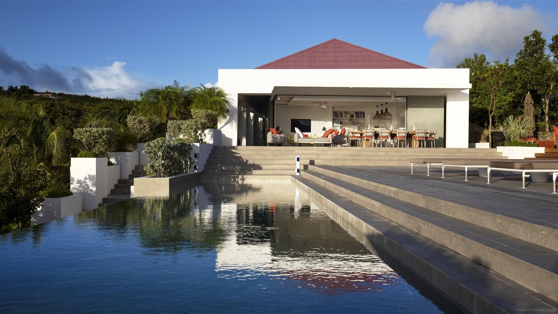 Ein modernes Gebäude mit Pool, Außenbereich und Treppen zu einer überdachten Fläche.