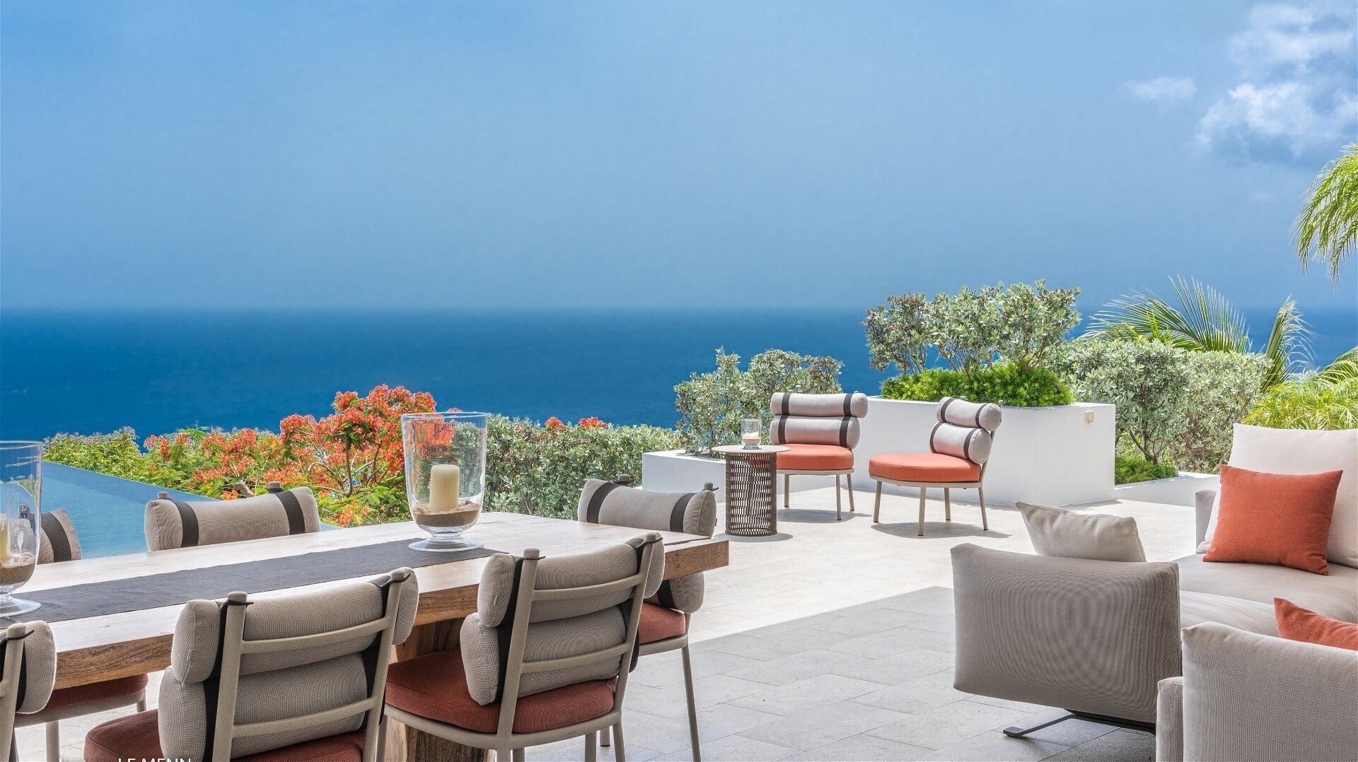 Een terras met uitzicht op de oceaan, met een tafel, stoelen en een bank.