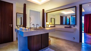 Une salle de bain moderne dotée d’un îlot central, de deux vasques et de grands miroirs.