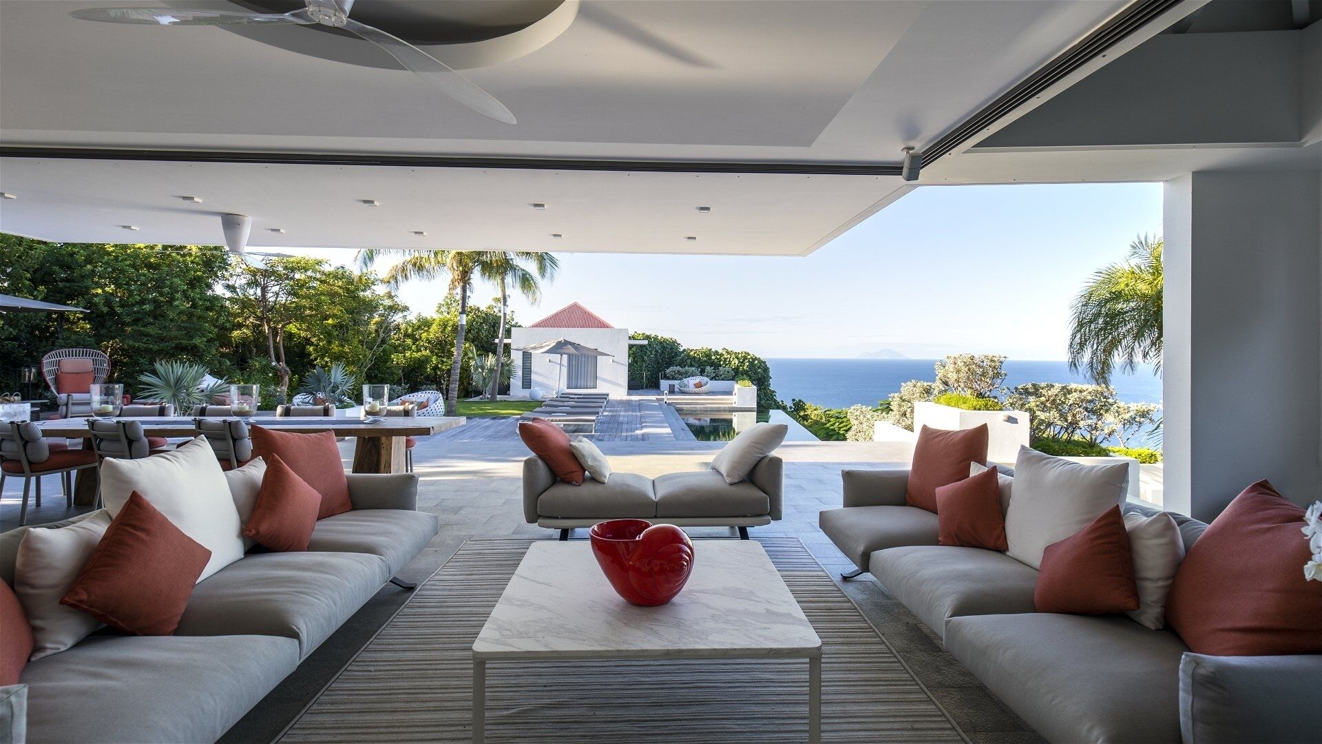 Ein moderner Außenbereich mit Pool, Sitzgelegenheiten und Blick auf den Ozean.