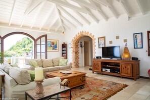 Amplia sala de estar con techo alto, televisor grande, mueble de entretenimiento de madera y una zona de estar acogedora con sofá y mesa de centro.