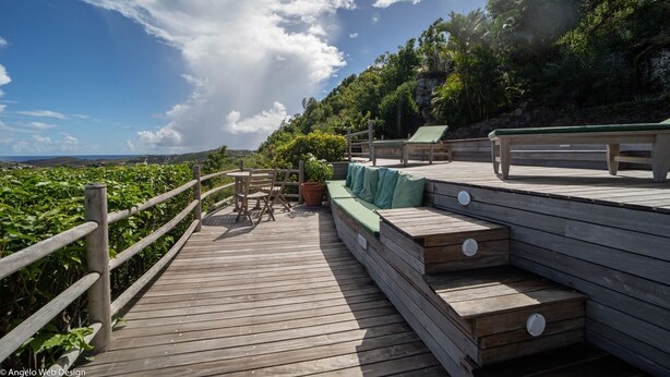 Eine Holzterrasse mit Sitzgelegenheiten und Blick auf die Landschaft.