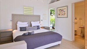 A modern bedroom with a large bed, bedside tables, and a view of the outdoors. - Belombre Luxury villa (Marigot)