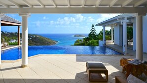 A pool with a view of the ocean and a covered patio area with seating. - Belombre Luxury villa (Marigot)