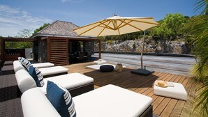 A wooden deck with outdoor seating, a pergola, and a stone structure.