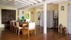 A dining area with a wooden table and chairs, a decorative wall panel, and a ceiling fan. - Manoir de Lurin Luxury villa (St Barths)