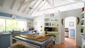 A kitchen with a large island, a window, and a view of the garden. - Manoir de Lurin Luxury villa (St Barths)