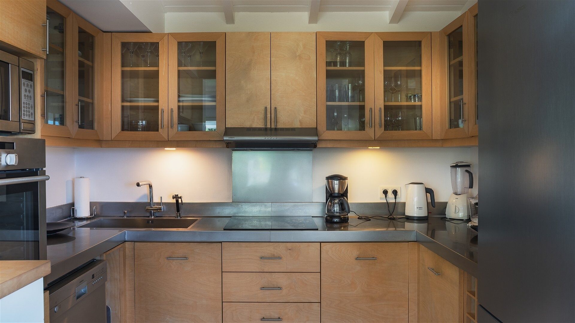 Een moderne keuken met houten kastjes, een roestvrijstalen spoelbak en een ingebouwde oven.