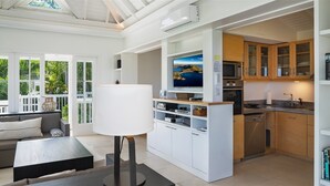 Un espacio moderno y abierto que combina la sala de estar y la cocina, con un televisor grande, armarios empotrados y un comedor.