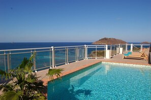 A pool with clear blue water, surrounded by a white railing, and overlooking a scenic ocean view with a distant island. - Ushuaia (1/4 Rooms) Luxury villa (Flamands)