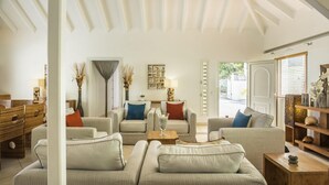 Un salon spacieux avec un plafond haut, un ensemble de canapés, une table basse et une bibliothèque.