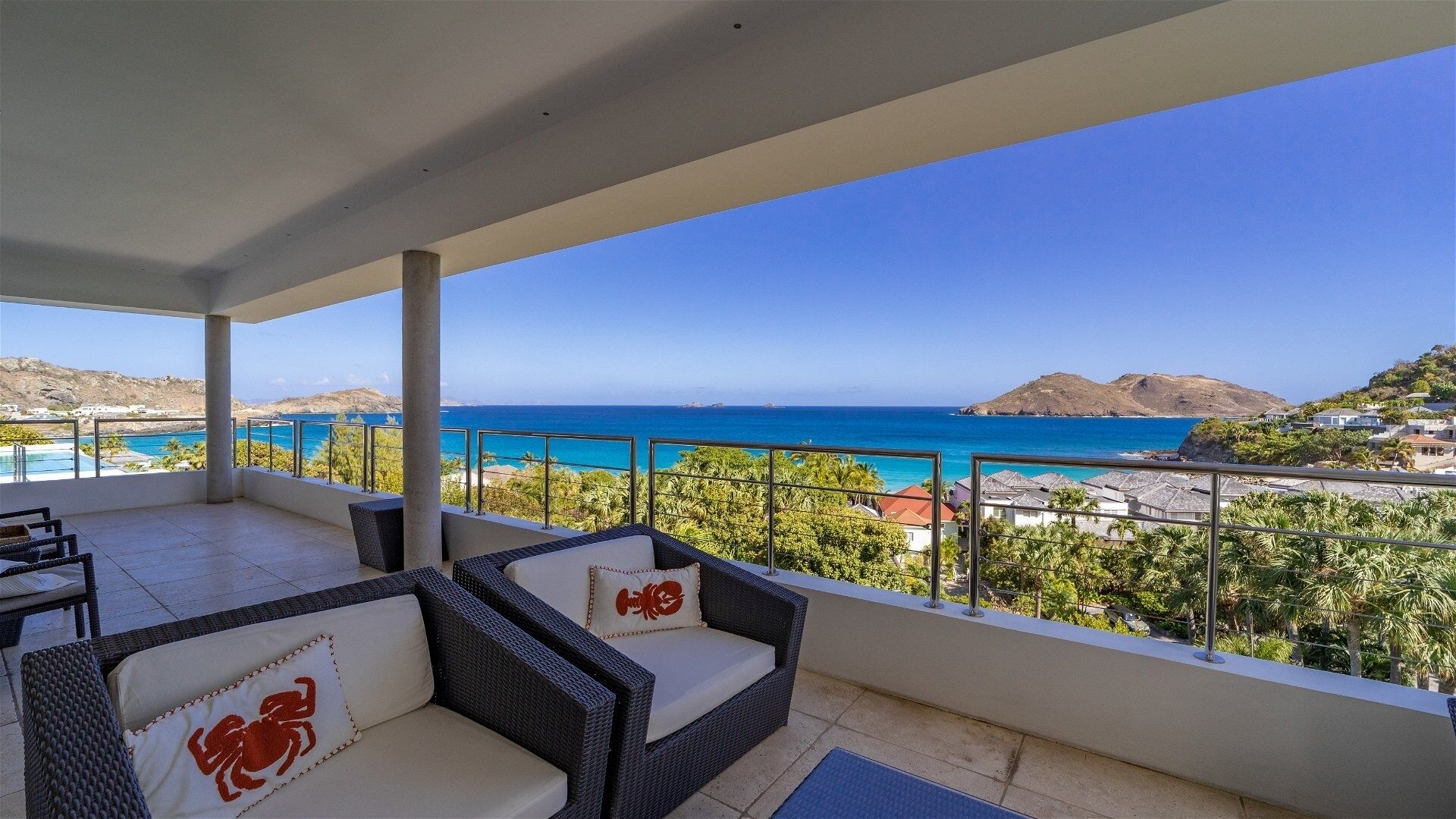 A balcony with wicker furniture and a view of the sea.