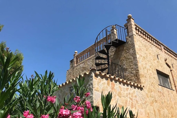 A stone building with a spiral staircase and a balcony.