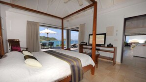 Ein Schlafzimmer mit einem großen Bett, einem Fernseher und Meerblick.
