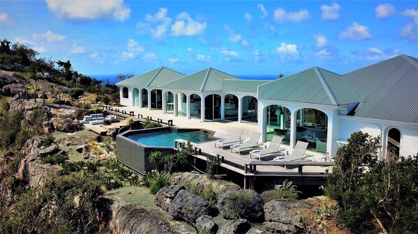 Un complexe hôtelier doté d’une piscine, de chaises longues et offrant une vue sur l’océan.