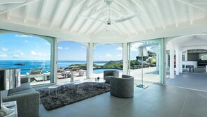 A spacious living area with a large window overlooking a pool and the ocean. - Beautiful Byzance Luxury villa (St Barts)