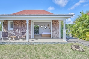 A house with a covered porch, a bed, and a dining area.