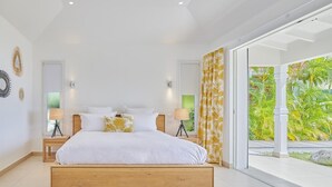 Een moderne slaapkamer met een groot bed, twee nachtkastjes met lampen, uitzicht op groen en een wit plafond.