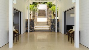 Interior modern amb una escala central flanquejada per parets de pedra i plantes en testos, que condueix a una estança fosca a la part superior.
