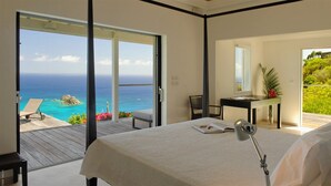 Ein Schlafzimmer mit einem Bett, einem Schreibtisch mit Stuhl und Meerblick.