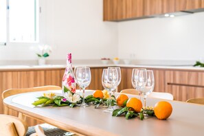 A dining table set with wine glasses, a floral-patterned bottle, and fresh oranges and greens. - Finca Son Vivot with swimming pool in Mallorca (Sa Pobla)