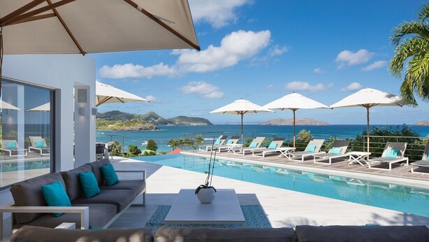 A poolside area with lounge chairs and umbrellas, overlooking a clear blue sea and distant islands. - Avenstar Luxury villa (Camaruche)