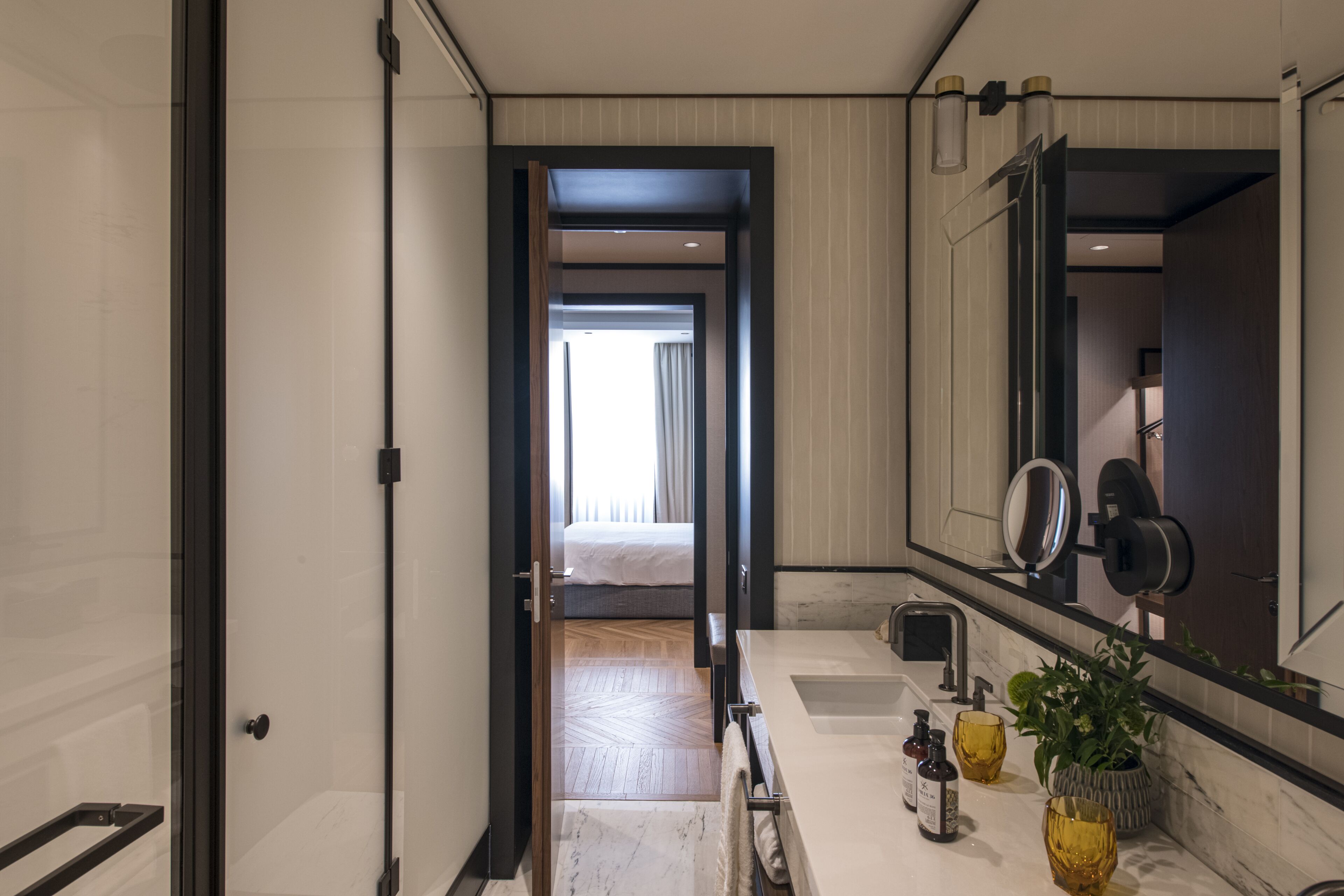 A modern bathroom with a large mirror, a sink, and a shower area.
