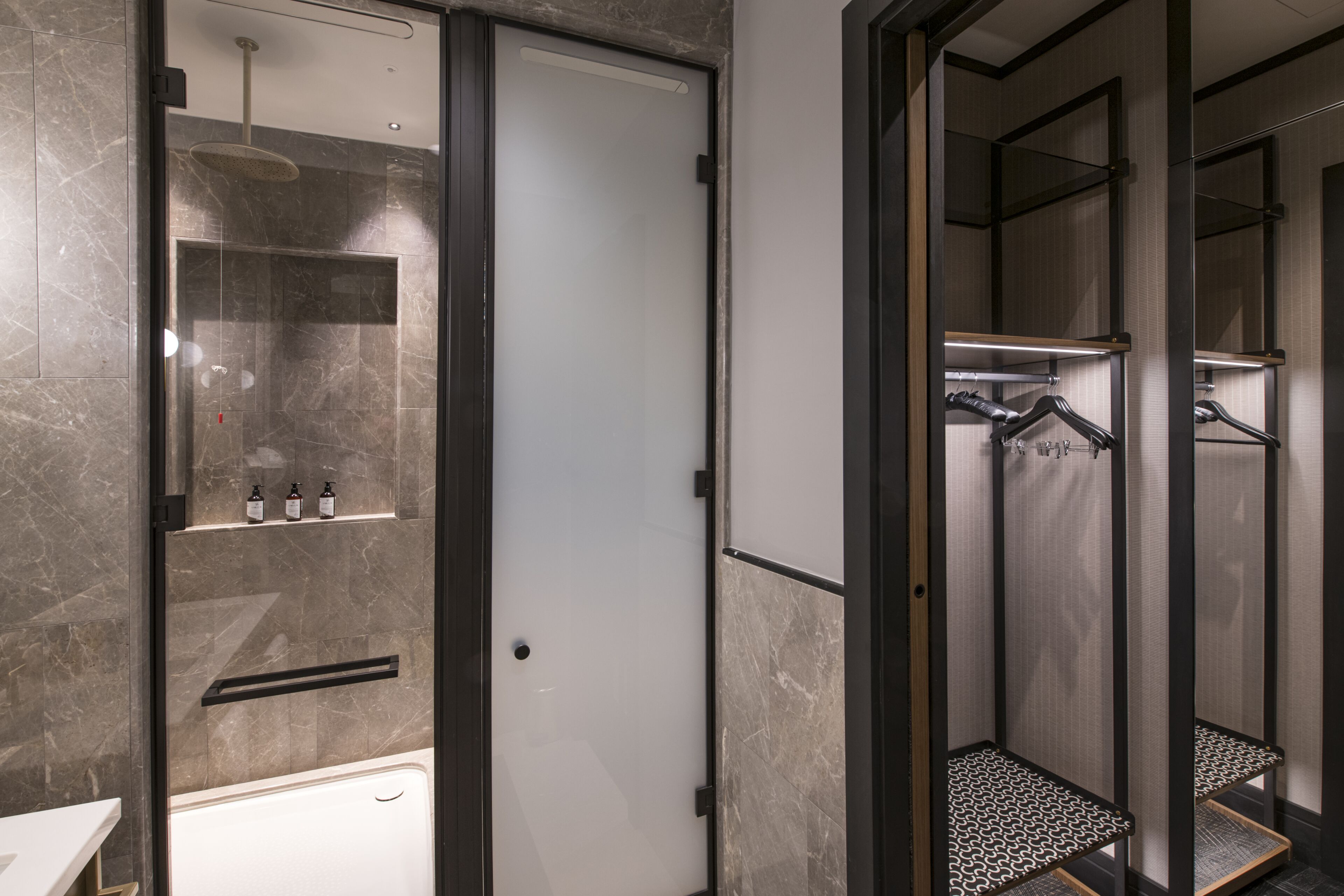 A modern bathroom with a glass-enclosed shower, a white bathtub, and a towel rack.