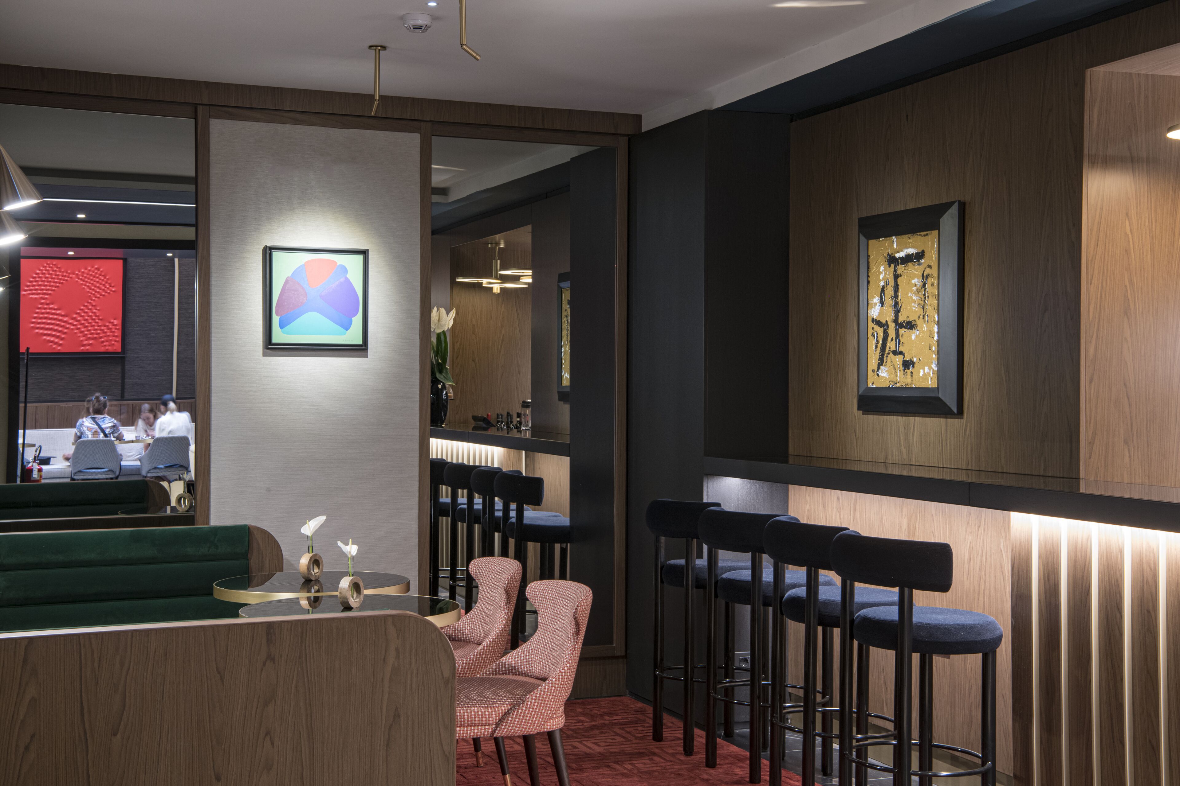 Un espace bar moderne avec des tabourets hauts, un canapé vert et un comptoir.