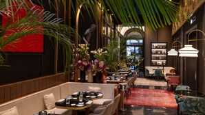 A modern interior with seating areas, decorative plants, and a red carpet.