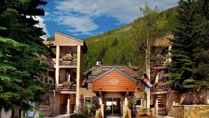 Eine Lodge mit mittlerem Eingang, mehreren Balkonen und einem Bergpanorama.
