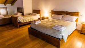A hotel room with two wooden beds, each with a headboard, bedside tables, and neatly folded towels. - Appartamento "Orchidea", Agriturismo dai Gobbi (Fara Vicentino)