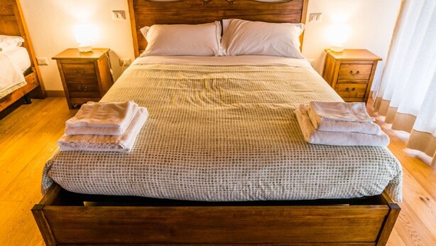 A neatly made bed with a patterned bedspread, two bedside tables with lamps, and a wooden floor. - Appartamento "Orchidea", Agriturismo dai Gobbi (Fara Vicentino)