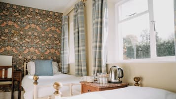 A bedroom with two beds, a wooden nightstand, a kettle, and a window with curtains.